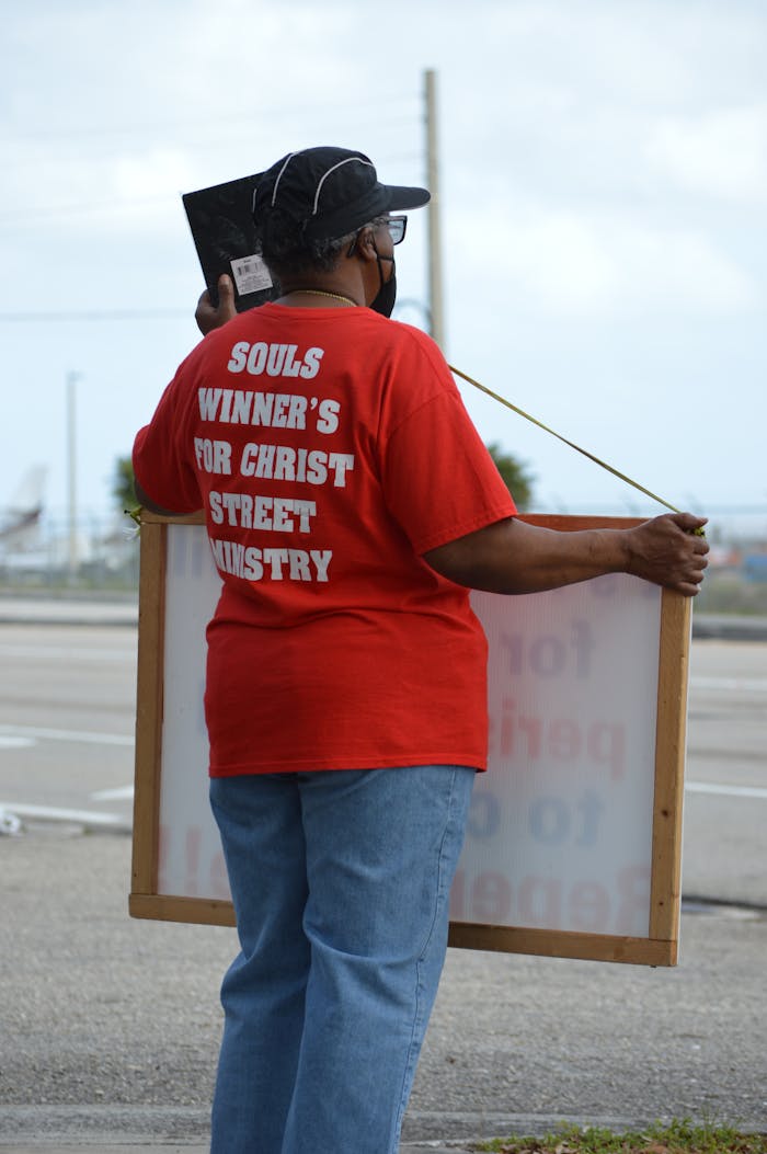 Female volunteer holding a cardboard donation sign in a charity setting.
